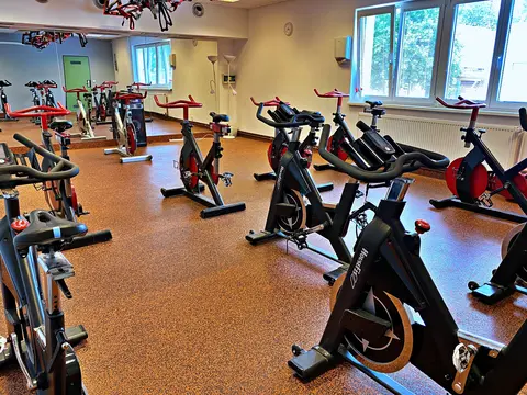 Sál s černými a červenými indoor cycling koly, zrcadly a okny