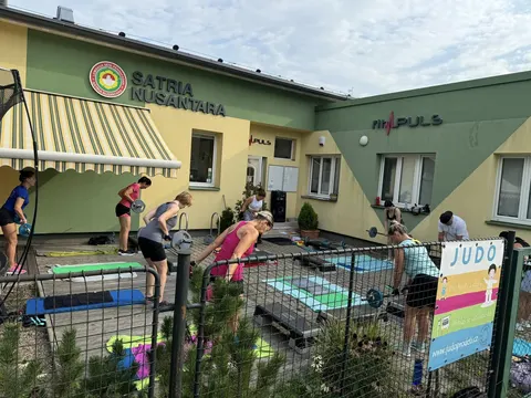 Skupina cvičí s činkami na stepech venku před budovou FitPULS