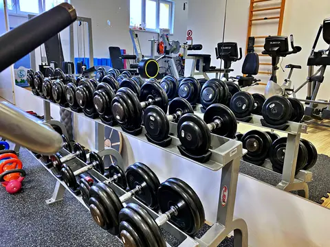Stojan s jednoručními činkami před zrcadlem a kettlebell činky na podlaze